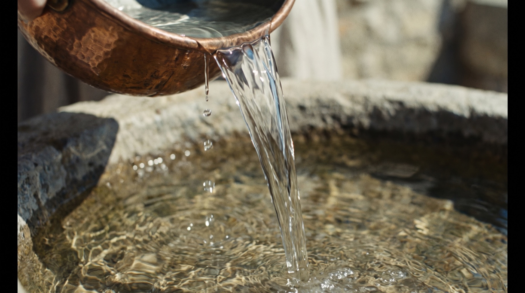 Acqua limpida versata da un vaso di rame